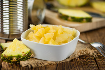 Portion of Chopped Pineapple (preserved) on wooden background, selective focus