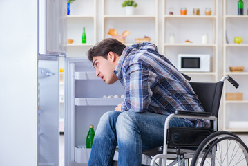 Young disabled injured man opening the fridge door 