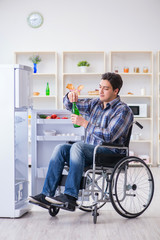 Young disabled injured man opening the fridge door 