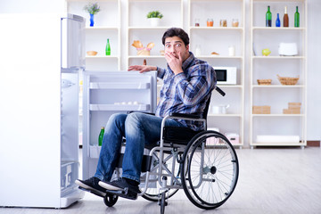Fototapeta na wymiar Young disabled injured man opening the fridge door 