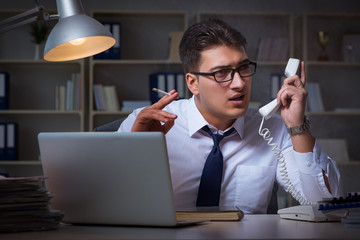 Businessman speaking on phone and smoking in office