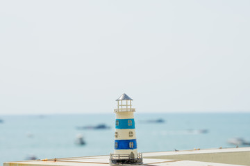 Small lighthouse model on the table with sea background