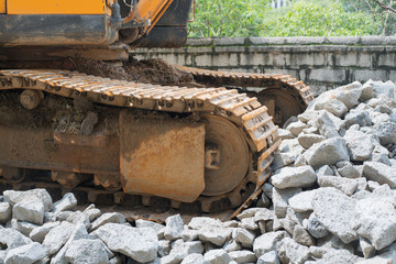 Fototapeta premium heavy organge excavator with shovel standing on hill with rocks