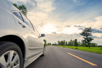 Car on road with green meadow and sunset background in Thailand