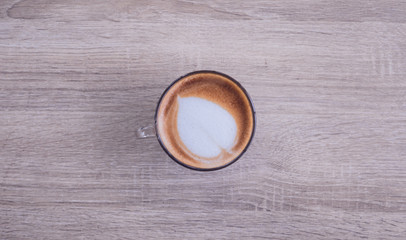 Vintage style of Hot coffee with heart make up on face of milk cream in glass cup on wooden table background, top view