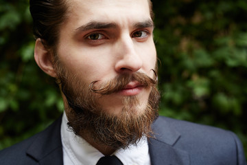 Young employee with beard and moustache looking at camera