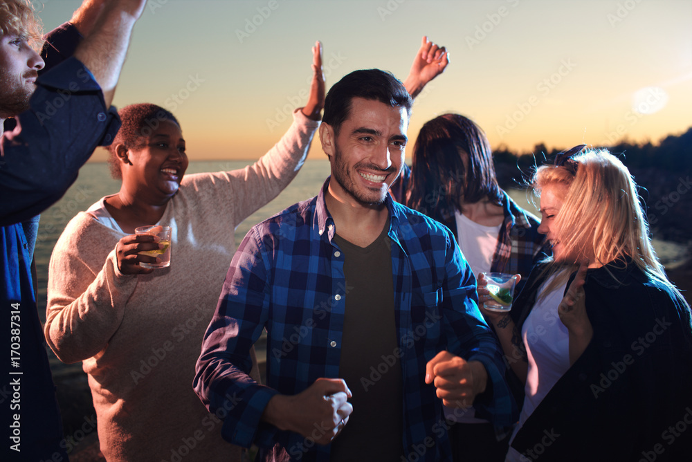 Poster ecstatic guys and girls dancing in the dusk on the beach