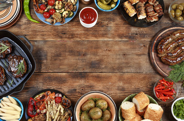 Outdoors Food Concept. Delicious barbecued steak, sausages and grilled vegetables on a wooden...