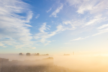 Heavy fog on the river and forest in calm morning weather. View of the residential buildings through the haze.morning urban landscape. Foggy City.Houses Protruding Through Fog.