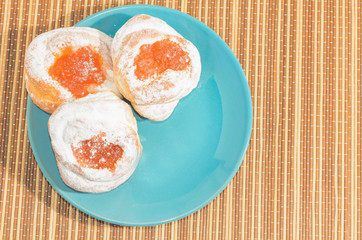 Appetizing homemade buns with orange fruit jam on a blue plate