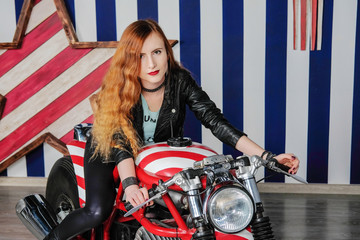 Fototapeta na wymiar Young attractive woman dressed in leather sitting on a motorcycle in the studio.