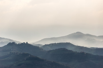 Green hills and trees in the foreground, mist and other hills and mountains in the background