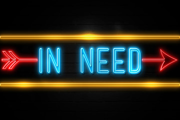 Obraz premium In Need - fluorescent Neon Sign on brickwall Front view