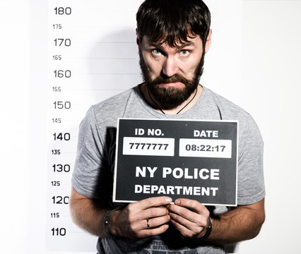 bearded man in handcuffs holds a sign, Criminal Mug Shots