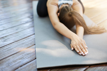 Close up of hands doing yoga or pilates laying on a grey mat in a temple or a backyard.