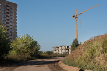 Fototapeta na wymiar Two Building cranes and building under construction against blue sky