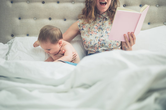 Mother in bed reading to her excited baby