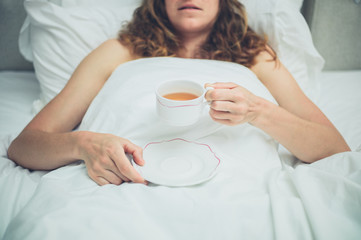 Young woman drinking tea in bed