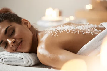 Poster Beautiful african girl resting relaxing with sea salt on back in spa salon. © Cookie Studio