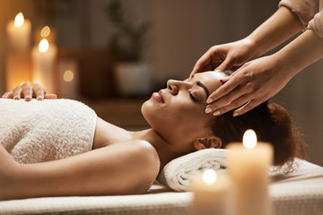 Attractive african girl enjoying face massage in spa salon. - 170397372
