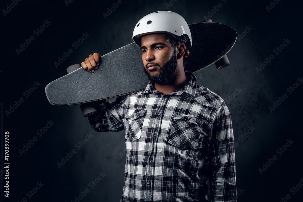 Wall mural A man holds long board over grey background in a studio.