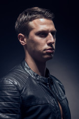 Obraz premium head and shoulders shot, one young adult man Caucasian, black background, studio, head headshot face, leather jacket, portrait