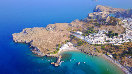 Obraz premium Aerial drone photo of famous beach of Lindos with turquoise waters and iconic ancient Acropolis - village of Lindos, Rodos island, Aegean, Dodecanese, Greece