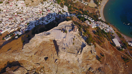 Aerial drone photo of famous beach of Lindos with turquoise waters and iconic ancient Acropolis - village of Lindos, Rodos island, Aegean, Dodecanese, Greece