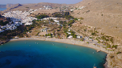Aerial drone photo of famous beach of Lindos with turquoise waters and iconic ancient Acropolis - village of Lindos, Rodos island, Aegean, Dodecanese, Greece