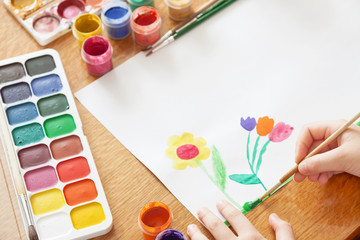 A child draws flowers by paint. Selective focus