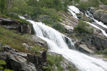 Waterfall in mountains of Norway in rainy weather.