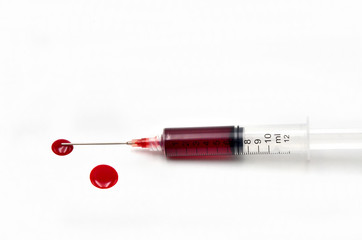 Syringe with blood on a white background close up