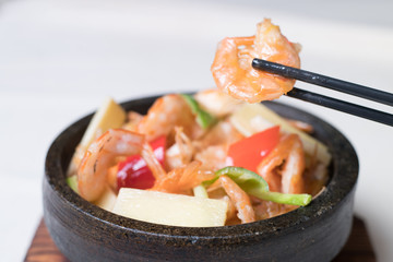 Shrimp stir fry in a wok with serving plates in the background
