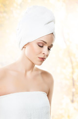 Portrait of young, beautiful woman with bath towel on her head: over orange background. Healthcare, spa, makeup and face lifting concept.