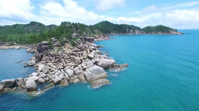 An aerial shot of rocks and stones and ocean. Background shows mountains