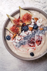 Blueberry banana smoothie bowl with figs and coconut on metal background. Flatlay, close up.