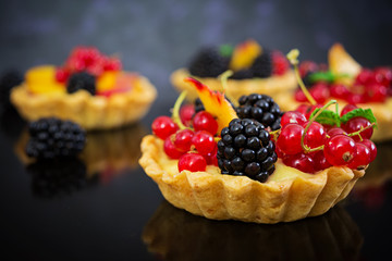Tartlets with different berries on dark background
