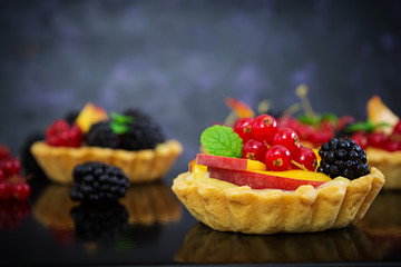 Tartlets with different berries on dark background