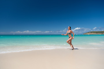 Woman in sexy swimsuit running on beach