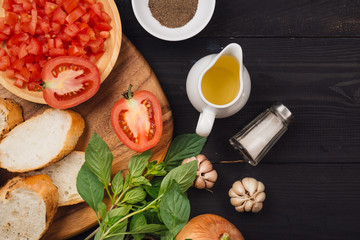 Preparing delicious Italian tomato bruschetta with chopped vegetables, herbs and oil