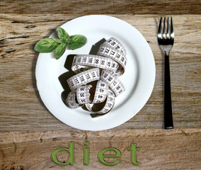 Concept diet - plate with measure tape and fork on wooden table with diet writing