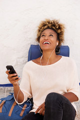 Fototapeta premium Smiling young woman traveler listening music with earphone outdoors