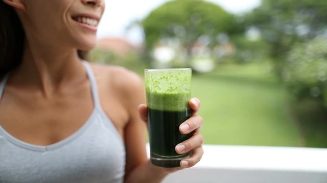 Green Juice - Happy Young Woman Holding Glass Of Fresh Vegetable Juice. Close up of green smoothie.