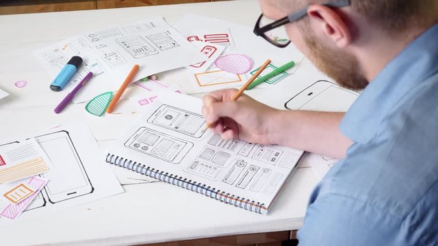 UX designer sketching prototype of a new app in his notebook