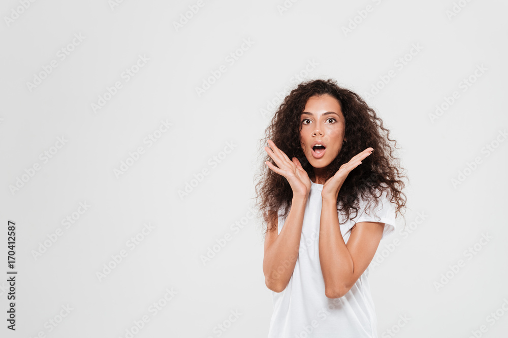 Poster Shocked curly woman holding hands near the head