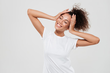 Fototapeta premium Pleased woman with closed eyes holding hands on head