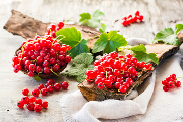 The leaves and berries of red currant on piece of old wood and in a bowl
