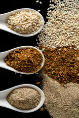 porcelain spoons with spices on a black background isolated