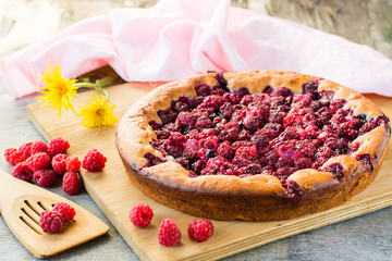 Delicious pie with raspberries on a wooden board