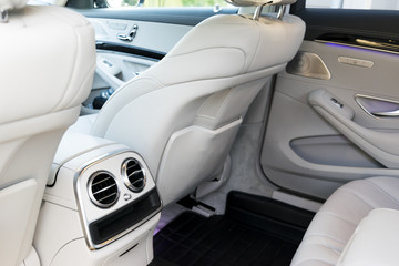 White leather interior of the luxury modern car. Leather comfortable white seats and multimedia. exclusive wood and metal decoration. Modern car interior details.